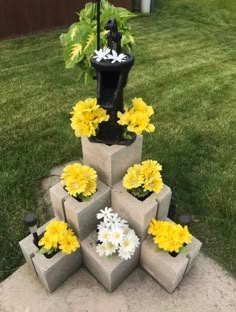 a small fountain made out of cinder blocks with flowers in the middle and a statue on top