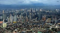 an aerial view of a city with tall buildings and mountains in the backgroud