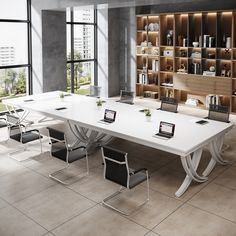 a large white table with two laptops on it in front of a bookshelf