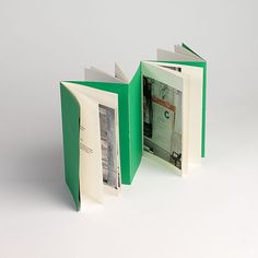 an open green book with pictures inside on a white surface, showing the front and back pages