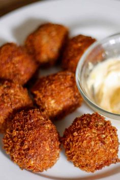 some fried food on a white plate next to a small bowl of mayonnaise