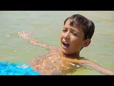 a young boy swimming in the water with a blue frisbee behind his back