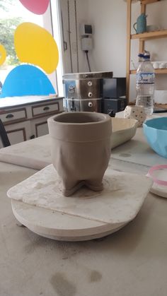 a pottery bowl sitting on top of a table next to other bowls and plates in front of a window