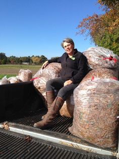 a woman sitting on the back of a truck filled with bags