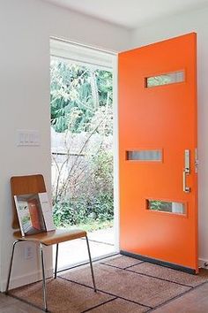 an orange front door with a chair in the foreground and a window on the far side