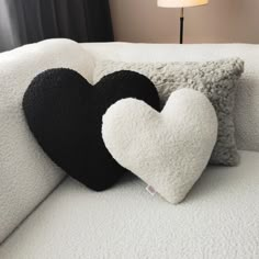 two black and white heart shaped pillows on a couch with a lamp in the background