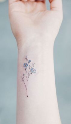 a small blue flower tattoo on the left side of the wrist is shown in this image