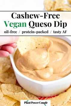 a hand dipping a tortilla chip into a bowl of cashew - free vegan queso dip