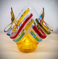 there are many different colored glasses in the glass vase on the table, and one is upside down