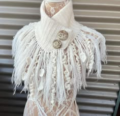 a mannequin wearing a white dress with fringes and buttons on it's chest