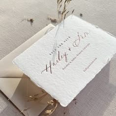 the wedding stationery is laid on top of an envelope with dried flowers in it