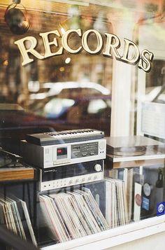 an old record player is in the window of a music store with records on display