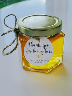 a jar filled with honey sitting on top of a white table next to a brown string