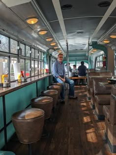 a man sitting in the back of a bus filled with lots of seats and tables