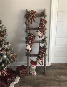 a christmas tree with stockings hanging from it next to a ladder decorated with santa's stocking