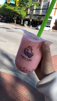 a person holding up a pink drink with a green straw