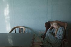 a woman sitting in a chair next to a table