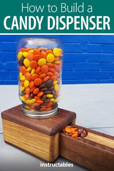 a jar filled with candy sitting on top of a wooden block next to a blue wall