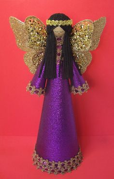 a purple and gold angel figurine on a pink background with glitters around it