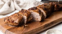 a wooden cutting board topped with sliced meat