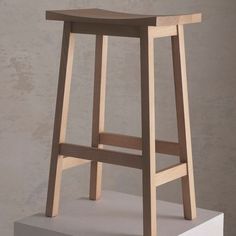 a small wooden stool sitting on top of a white platform in front of a wall