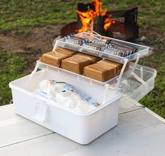 an ice chest filled with marshmallows next to a campfire on a picnic table