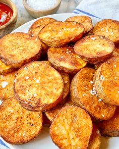 a white plate topped with fried potatoes next to ketchup