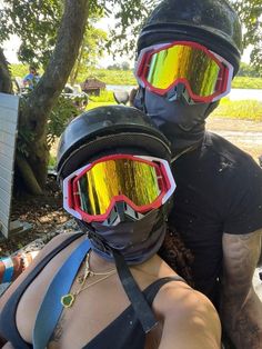 two people wearing ski goggles and protective gear on their faces, one person has his arm wrapped around the other's shoulder