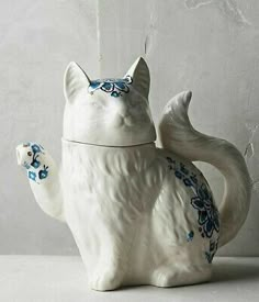 a white ceramic cat with blue flowers on its tail