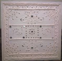 an intricately carved white tile with holes in the middle and small circles on it