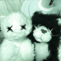 two black and white teddy bears with crosses on their eyes sitting next to each other