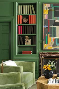 a living room with green walls and bookshelves filled with books on top of them