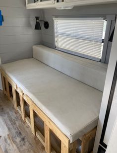 a couch made out of wooden pallets in a room with white walls and cabinets