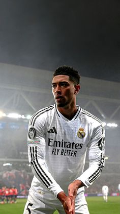 a man standing on top of a soccer field in front of a stadium filled with people