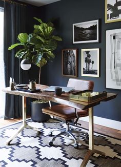 a room with blue walls and pictures on the wall, including a desk in front of a potted plant