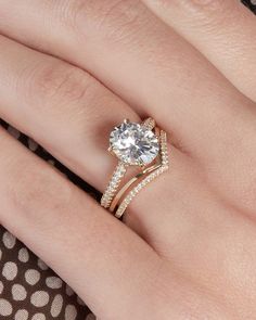 a woman's hand with a gold ring and diamond engagement ring on her finger