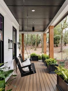 a porch with some plants on it and a swing chair hanging from the front door