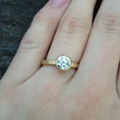 a woman's hand with a gold ring and a white diamond on her finger