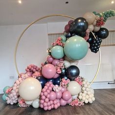 an arrangement of balloons and flowers in a circle on top of a wooden floor next to a wall