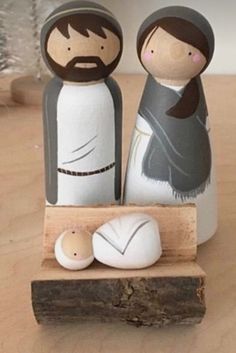 two wooden figurines are standing next to each other on a piece of wood