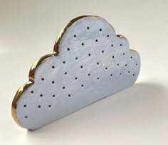 a white cloud shaped brooch sitting on top of a table