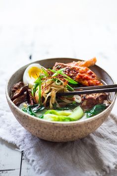 a bowl filled with meat and veggies on top of a white table cloth