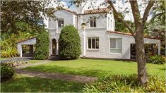 a white house surrounded by trees and bushes