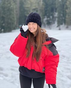 a woman in red jacket standing on snow covered ground