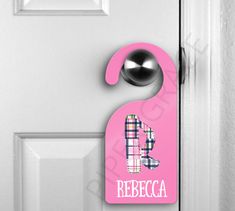 a pink door hanger with the letter b on it and a black ball hanging from it's side