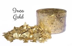 golden wings next to a metal canister filled with gold flakes on a white background