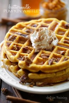 waffles with ice cream and nuts are on a plate next to a jar of honey