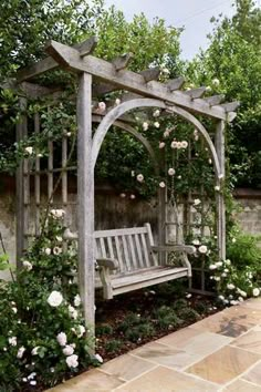 a wooden bench sitting in the middle of a garden with roses growing all around it