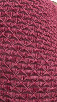 a close up view of the back of a red knitted sweater with an intricate pattern