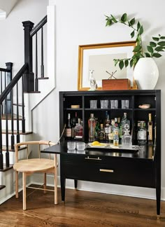 a black table with liquor bottles and glasses on it in front of a stair case